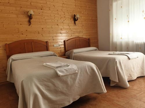 a room with two beds with white sheets and a window at Hostal Río Mundo in Riópar