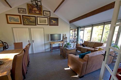 a living room with a table and chairs and a television at Het Jachthuus - Vakantiewoning Oscar Hoeve in Ede
