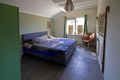 een slaapkamer met een bed, een stoel en een raam bij Het Jachthuus - Vakantiewoning Oscar Hoeve in Ede