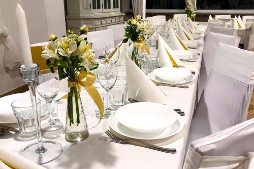 a long white table with white plates and flowers on it at Dom św. Józefa in Szczecin