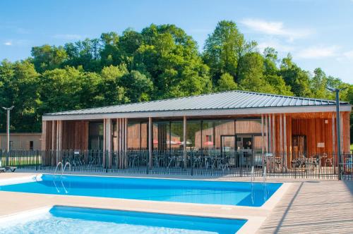 une maison avec une piscine à côté d'un bâtiment dans l'établissement Village de vacances Les Lambrilles, à La Bastide-de-Sérou