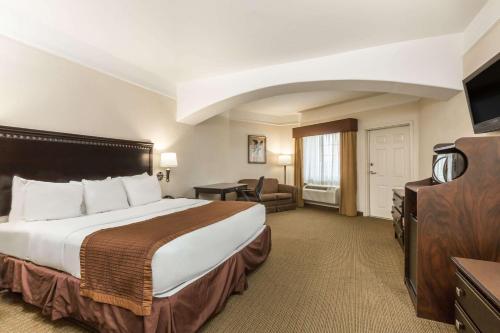 a hotel room with a bed and a television at Baymont by Wyndham Galveston in Galveston