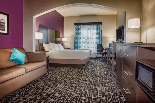 a hotel room with a bed and a couch at La Quinta Inn & Suits by Wyndham Pontoon Beach IL in Pontoon Beach