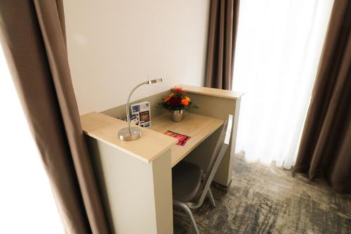 einen Schreibtisch mit einer Lampe und Blumen auf einem Zimmer in der Unterkunft Petul Apart Hotel An'ne 40 in Bochum