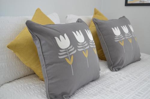 two grey pillows sitting on a bed with yellow pillows at PENTHOUSE in Shanklin