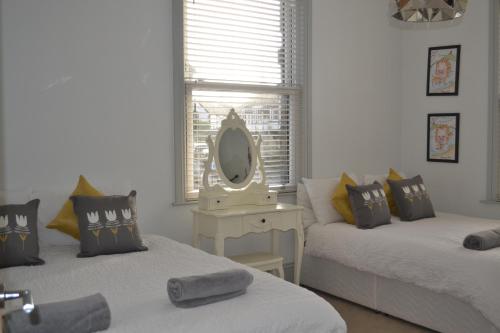 a bedroom with two beds and a mirror on a table at PENTHOUSE in Shanklin