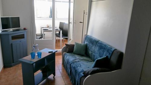 un salon avec un canapé bleu et une télévision dans l'établissement Lara 3 - T2 Loggia Piscine 2 lits doubles Parking Près du centre-port et île Loisirs, au Cap d'Agde