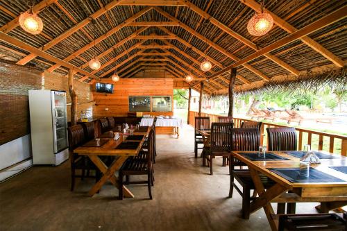 ein Restaurant mit Holztischen und -stühlen sowie einem Kühlschrank in der Unterkunft Bay Beach Hotel in Nilaveli