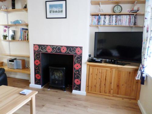 sala de estar con chimenea y TV de pantalla plana en Sunrise Cottage en Lowestoft