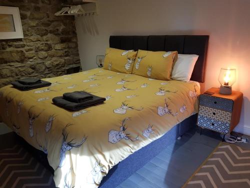 a bedroom with a bed with a yellow comforter at Hawks Barn in Horton in Ribblesdale