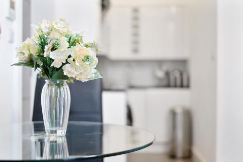 a vase of flowers sitting on a glass table at City Prime Apartments in London