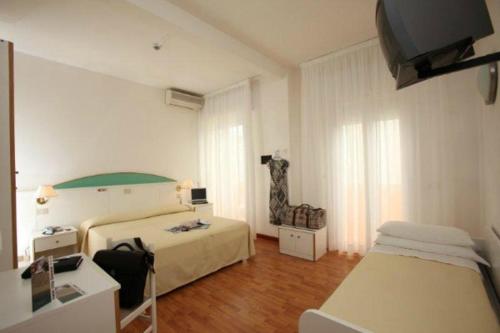 a hotel room with two beds and a chair at Hotel Villa Gioiosa in Lido di Jesolo