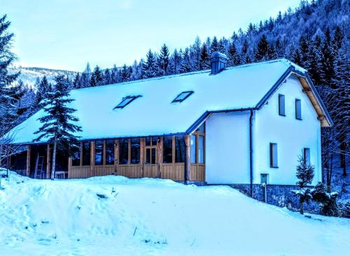 a house covered in snow with trees in the background at Rezidence Kouty in Loučná nad Desnou