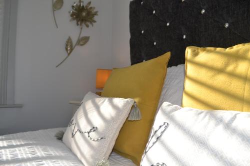 a bed with yellow and white pillows on it at PENTHOUSE in Shanklin