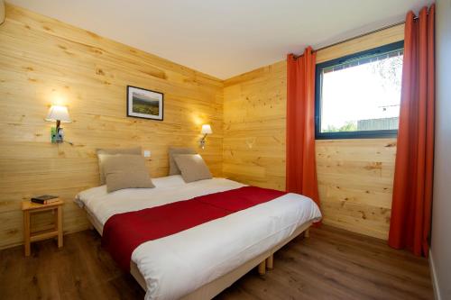 um quarto com uma cama grande e uma janela em Village de vacances Les Lambrilles em La Bastide-de-Sérou