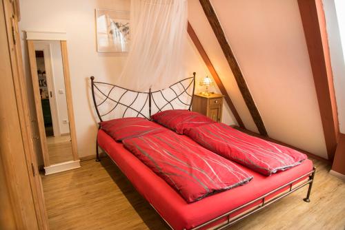 a red bed with two red pillows on it at RefuKium Altstadtscheune in Weißenburg in Bayern