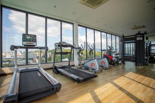 a gym with several tread machines in a room with windows at Cozy Living Sky Apartment in Kota Kinabalu