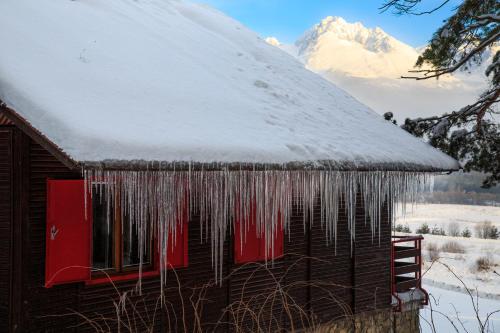 a house covered in icicles with a snow covered mountain at Chata Borik in Svit