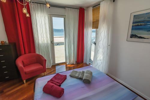 een slaapkamer met een bed en een rode stoel bij Apartment Mimi in Biograd na Moru