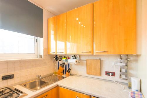 een keuken met houten kasten, een wastafel en een raam bij Apartment Mimi in Biograd na Moru