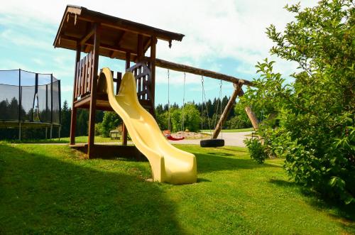 a yellow slide in a park with a playground at Lammerauhof in Abtenau