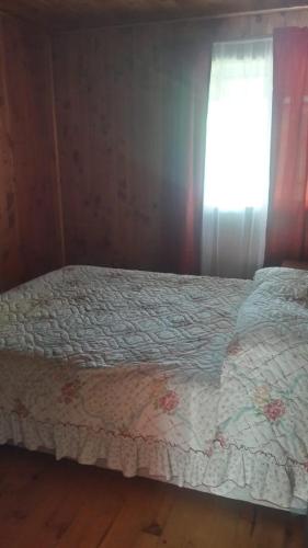 a bed in a room with a window with a bedspread at Cabaña Punta Diamante in Castro