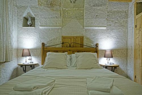 a bedroom with a large bed with two lamps on tables at Naraca Cave House in Goreme