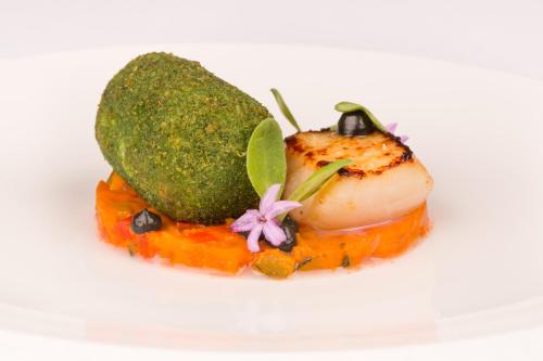 a piece of food on a white plate with broccoli at Fishmore Hall Hotel and Boutique Spa in Ludlow