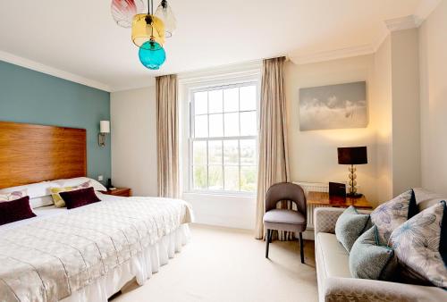 um quarto com uma cama, uma cadeira e uma janela em Fishmore Hall Hotel and Boutique Spa em Ludlow