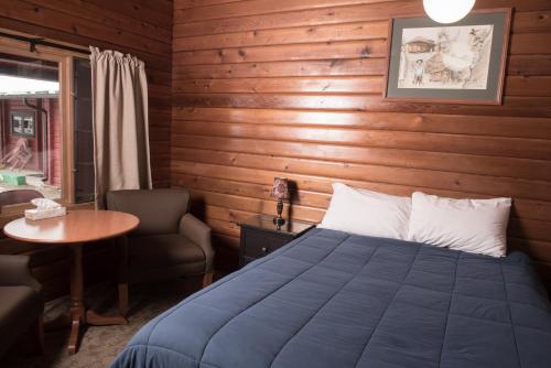 ein Schlafzimmer mit einem Bett, einem Tisch und einem Stuhl in der Unterkunft Miette Hot Springs Bungalows in Jasper