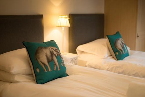 2 camas con almohadas verdes y un perro en ellas en Haddon Cottage - Darwin Lake Holiday Village, en Matlock