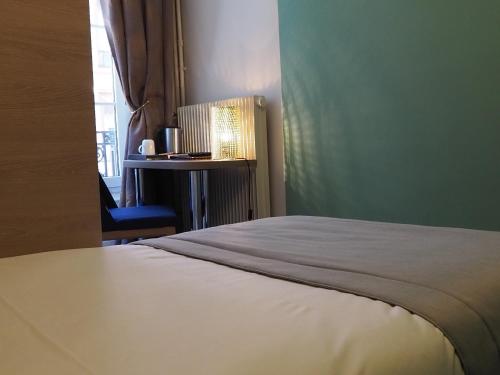 a bedroom with a bed and a chair and a window at Hôtel du Dauphin in Lyon