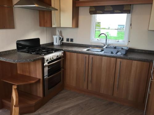 a kitchen with a stove and a sink and a window at 'Hartland Caravan' with Sea Views in Bideford