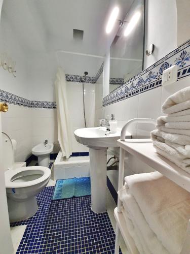 a white bathroom with a toilet and a sink at Casa Rural El Pinar de Jesus in Arcos de la Frontera