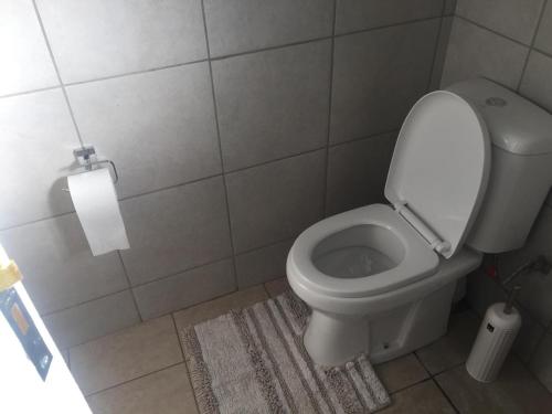 a bathroom with a toilet and a roll of toilet paper at Green Grove Villa in Centurion