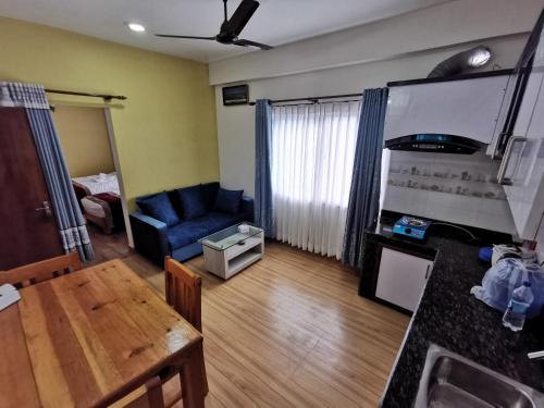 a living room with a table and a blue couch at DnD Apartment Pokhara in Pokhara