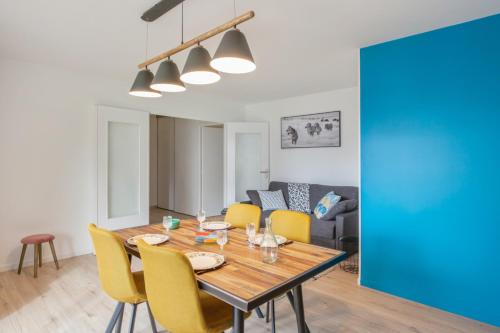une salle à manger avec une table en bois et des chaises jaunes dans l'établissement Appartement Ribera - Welkeys, à Annecy