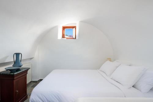 a bedroom with a white bed and a small mirror at Aquaria Villa in Karterados