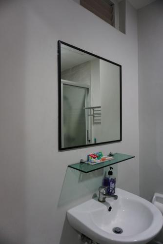 een badkamer met een wastafel en een spiegel aan de muur bij Cozy condo unit 5mins from Mactan Cebu Int'l Airport with Netflix in Mactan