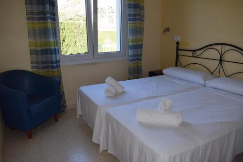 - une chambre avec deux lits et une chaise bleue dans l'établissement Anacasa Malibu Beach Oliva Nova MET AD1000, à Oliva