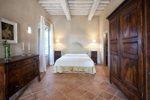 a bedroom with a bed and a wooden dresser at Casanova di Neri Relais in Montalcino