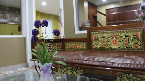 a bedroom with a bench with a vase with purple flowers at GRANADA INN PALU in Palu