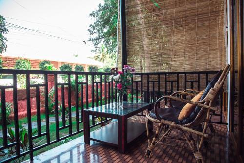 a patio with a table and a chair on a balcony at Patnem Beach Cottages in Patnem