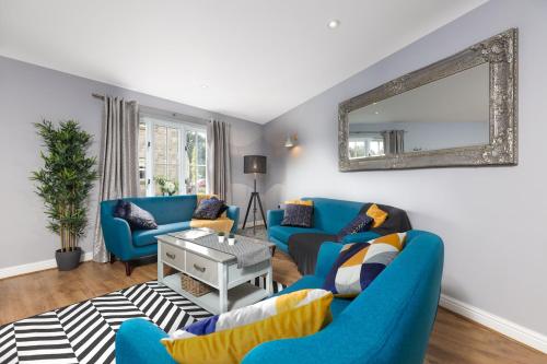 a living room with two blue couches and a mirror at Hopton Cottage - Darwin Lake Holiday Village in Matlock