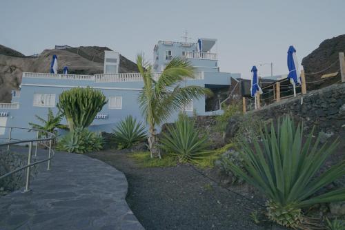 a walkway leading to a white building with palm trees at Sur Restinga in La Restinga