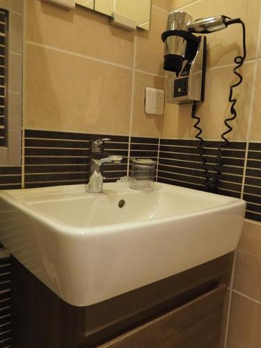 a white sink in a bathroom with black tiles at Hôtel du Dauphin in Lyon