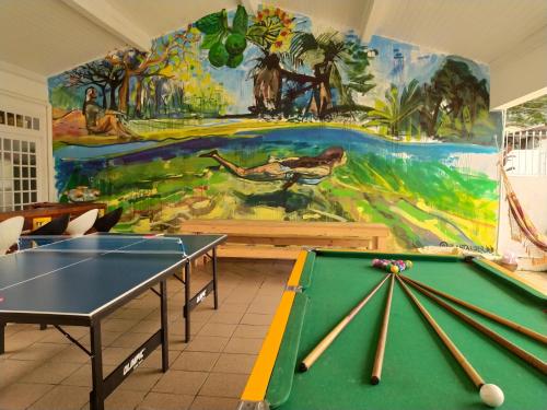 a room with two ping pong tables and a mural at Pequi hostel in Florianópolis