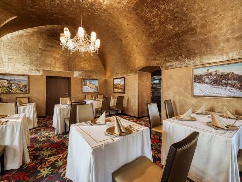 een eetkamer met tafels en stoelen en een kroonluchter bij Penzión Gurmen in Stará Ľubovňa