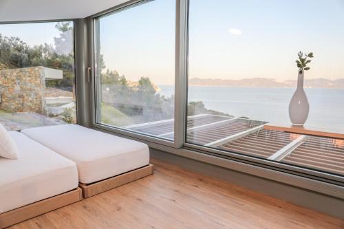 a bedroom with a large window with a view of the ocean at Thalasses Villas Skiathos in Skiathos Town