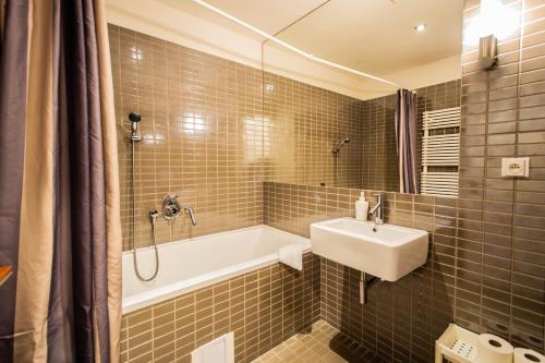 een badkamer met een wastafel, een bad en een spiegel bij Ruterra Apartment with Garage in Praag